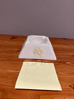 Front view of square ceramic ashtray with floral embossed decoration and note saying Lot 55.