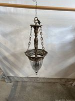 Full view of antique chandelier hanging showing brass frame and glass shade