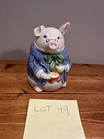 Image showing the full pig-shaped sugar bowl holding a yellow cup and saucer with details on the base and overall shape.