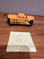 Yellow model train caboose CP Rail CP435678 on wooden surface with lot label.