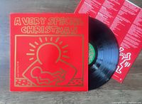 Photo of the album cover, vinyl record and insert for "A Very Special Christmas" LP with red cover and Keith Haring artwork.