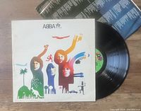 Photo showing ABBA 'The Album' vinyl record partially out of its cover with the lyrics insert visible in the background.