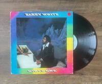 Photo of Barry White Stone Gon' vinyl LP album with cover and the record partially pulled out on wooden floor