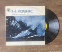 Photo of the vinyl LP 'Surfin' With Bo Diddley', showing the front album cover with a surfer image and the record partially pulled out.