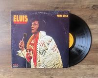 Vinyl LP record partially removed from original album cover featuring Elvis Presley in white sequined stage costume.