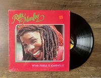 Photo showing the vinyl record partially removed from the red album cover with a close-up photo of Rita Marley smiling on the front cover. The orange price sticker is visible.