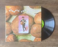 Vinyl LP record partially removed from its album cover showing the label and grooves.