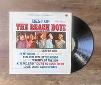 Photo of vinyl LP 'Best Of The Beach Boys' with cover showing the band members and song list. Vinyl partially visible.