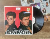 Photo shows front cover of WHAM! LP titled 'Fantastic' featuring members' portraits on red background and the vinyl record partially visible.
