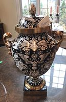 Front view of the full lidded vase on tabletop against window background