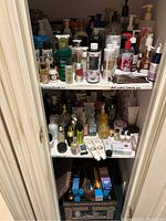 Closet shelf showing two tiers of bottles and jars of shower gels, lotions, soaps