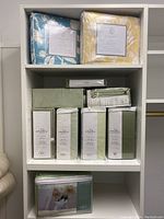 Overview of two patterned king size sheet sets on top shelf, multiple green Amadeus QVC sheet sets on middle shelf and floral duvet cover on bottom shelf