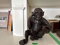 Front view of brass chimpanzee figurine wearing glasses and reading a book