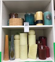 Wide view of two shelves filled with various candles in different sizes and colors including battery-operated candles.