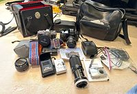 Overview of two Canon SLR bodies, assorted lenses, flash unit and carrying cases on countertop