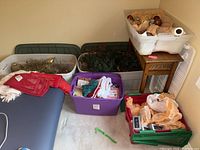 Overview of plastic bins containing various holiday items: napkins, towels, hats, garland, boughs and ornaments