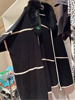 Black wrap coat with faux fur collar hanging on rack