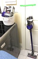 Assembled vacuum leaning against door with separate components in woven basket