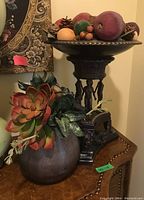 Both bronze-style bowl with faux fruit and succulent vase displayed together on table
