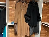 Both coats hanging in garment bags with hangers