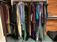 Rack of assorted women's dresses and suits on hangers in various colors and styles