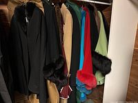 Eight coats and capes on wooden rack