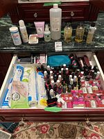 Top view showing assorted bottles and nail treatment products on countertop and heavily filled drawer with nail polish bottles and other accessories.