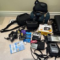 Overview of multiple cameras, camcorders, bags and media on floor