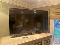 Front view of powered-off 65-inch Samsung TV on dresser showing screen and stand