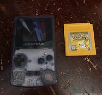 Console and cartridge laid flat on wooden surface, top-down view.