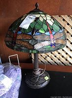 Full view of Tiffany style lamp showing dragonfly stained glass shade and ornate metal base.