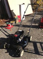 Full view of the black Yard Machines push lawn mower showing engine, wheels, handle and deck.