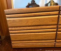 Front view showing oak night side table with three grooved drawer fronts and natural wood grain finish.