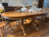 Overall front view of oak table with installed leaf and surrounding chairs