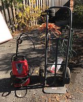 Husky power washer, Milwaukee dolly, and extension cords shown outdoors on pavement with foliage background.