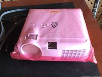 Optoma HD70 projector inside a pink plastic protective sleeve with ventilation and lens visible