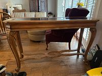 Front view of carved wood sofa table with beveled glass top, showing carved legs and detailing.