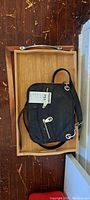 Wooden tray with handles and black Michael Kors leather purse placed inside