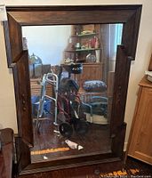 Front view of the large wall mirror showing the dark wood frame with decorative corners and accents.