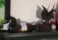 Photo showing the carved wood duck figure with smooth dark finish and carved detailing on head and beak, sitting on a flat surface.