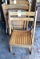 Front view of a single oak wood folding chair with slatted seat and two horizontal slats on the backrest.