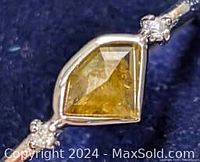 Close-up of the ring's yellow faceted diamond set in 10K gold viewed from an angle