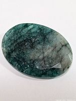 Close-up photo of the oval emerald gemstone showing color and natural inclusions.