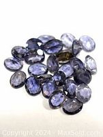 Multiple loose genuine iolite gemstones of various shapes and sizes shown in a group, highlighting the color and faceting.