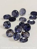 Photo of multiple faceted iolite gemstones in shades of blue and violet on a neutral background.