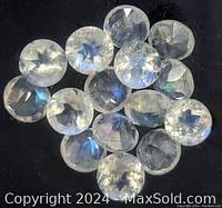 Close-up of translucent moonstone gems with visible adularescence and cabochon cut, arranged on a black surface.