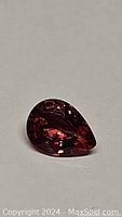 Pear-shaped padparadcha sapphire showing color and faceting from above.