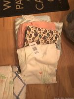 Photo showing the assortment of sheets and duvet cover folded and stacked on the floor, includes fabrics with floral, paisley, striped, and solid patterns.