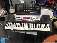 Top view of Yamaha electric keyboard on a table showing keys, buttons, and speakers.