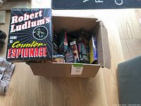 Cardboard box containing multiple used video game boxes and a prominent Robert Ludlum's Counter Espionage board game box on top